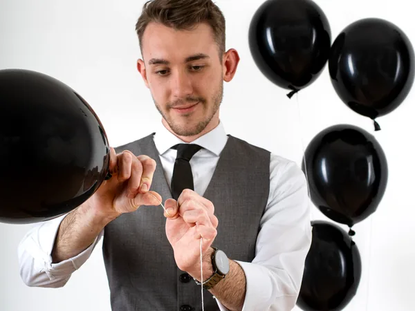 Maxi Muschaweck knotet die Schnur eines schwarzen Luftballons, weitere Ballons im Hintergrund.